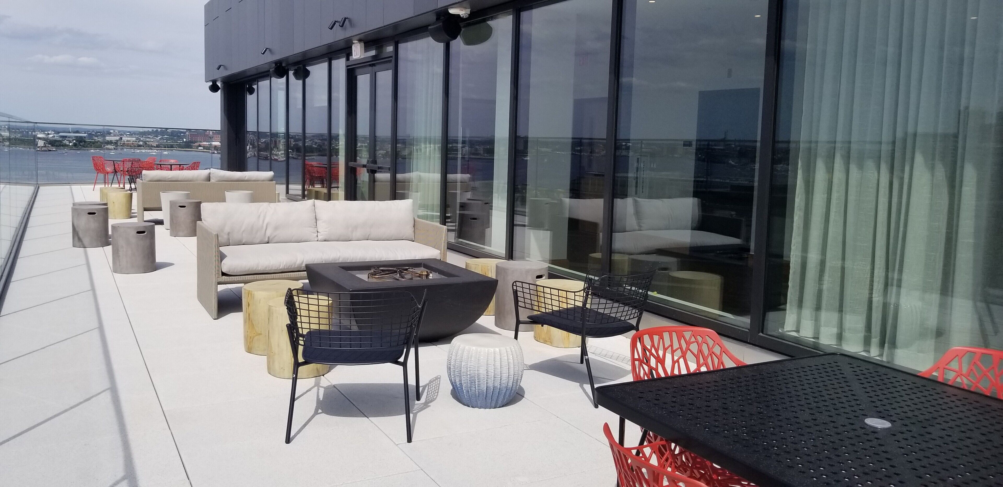A rooftop terrace with outdoor seating, a fire pit, and a view of the cityscape.