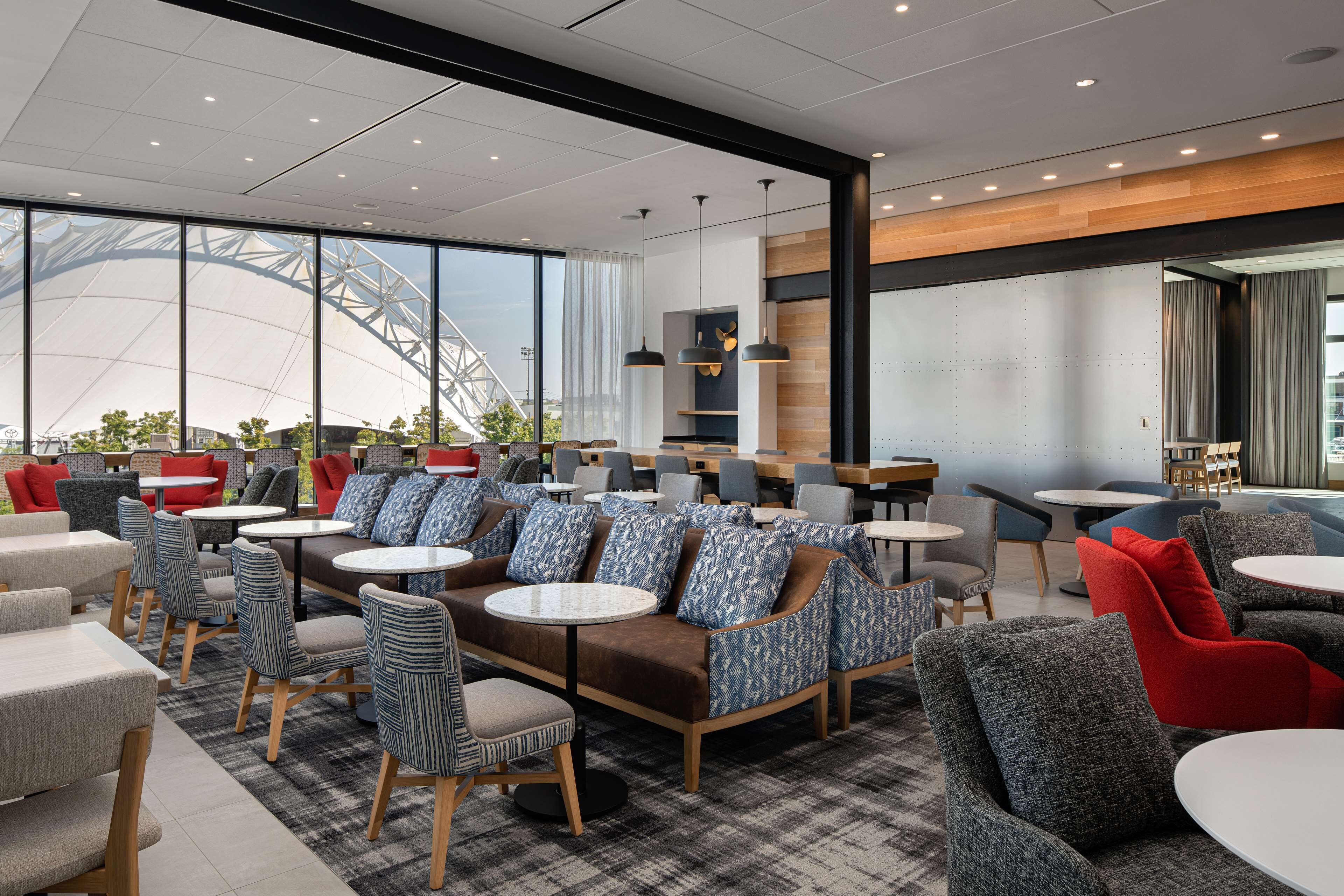 A modern cafe with seating arrangements including sofas and chairs, a large window with a view of a bridge, and a wooden accent wall.