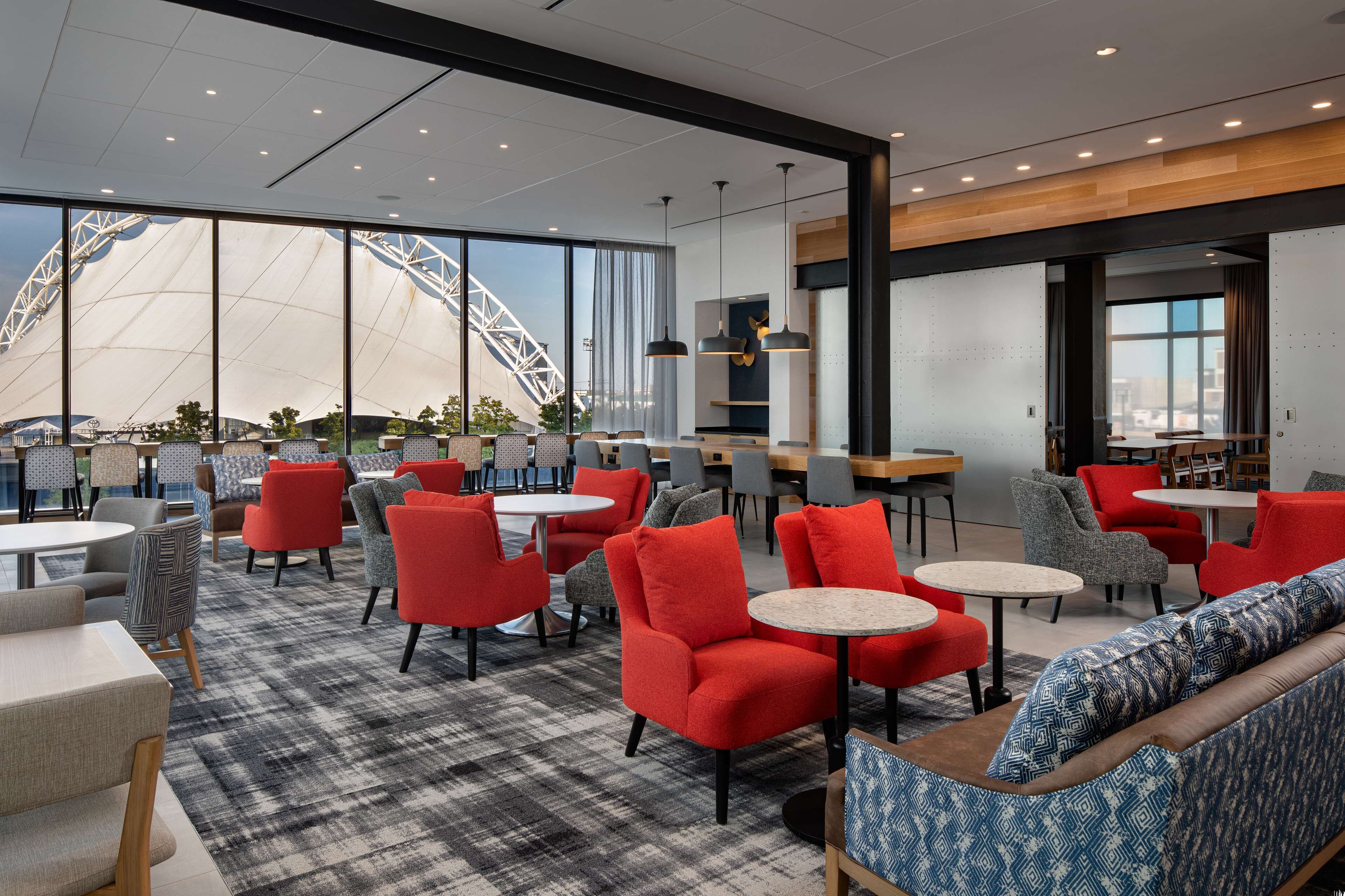A modern lounge area with red and grey seating, large windows, and a view of a Ferris wheel.