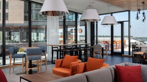 A modern dining area with a view of the city, featuring a mix of seating arrangements and contemporary lighting fixtures. - Hyatt Place Boston/Seaport District (Boston)