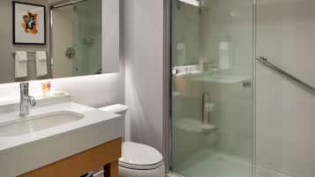 Un baño moderno con ducha de vidrio, lavamanos blanco y un inodoro.
