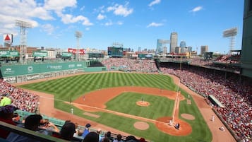 A baseball stadium with multiple levels of seating, a large crowd, and a city skyline in the background.