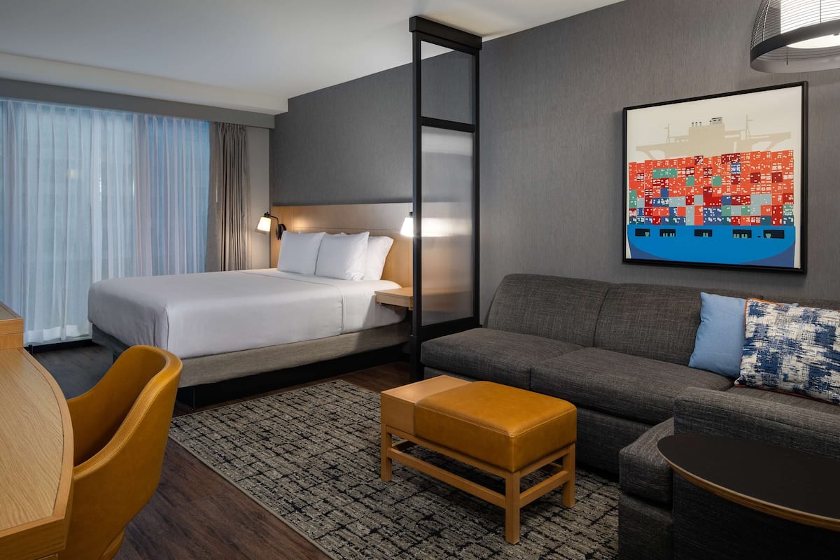 A hotel room with a bed, a sofa, a small table, and a chair.
