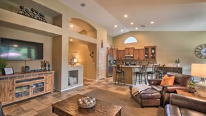 A spacious living room with a fireplace, a dining area, and a kitchen with wooden cabinets. - Spacious Surprise Home: 6 Mi to Wildlife World Zoo (Surprise)