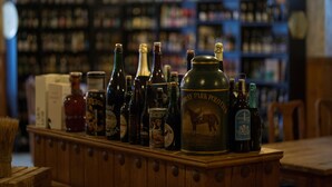 Eine Bar mit verschiedenen Flaschen und Kartons, darunter eine große, grüne Flasche mit dem Aufdruck 'Hedley Park Polo'.