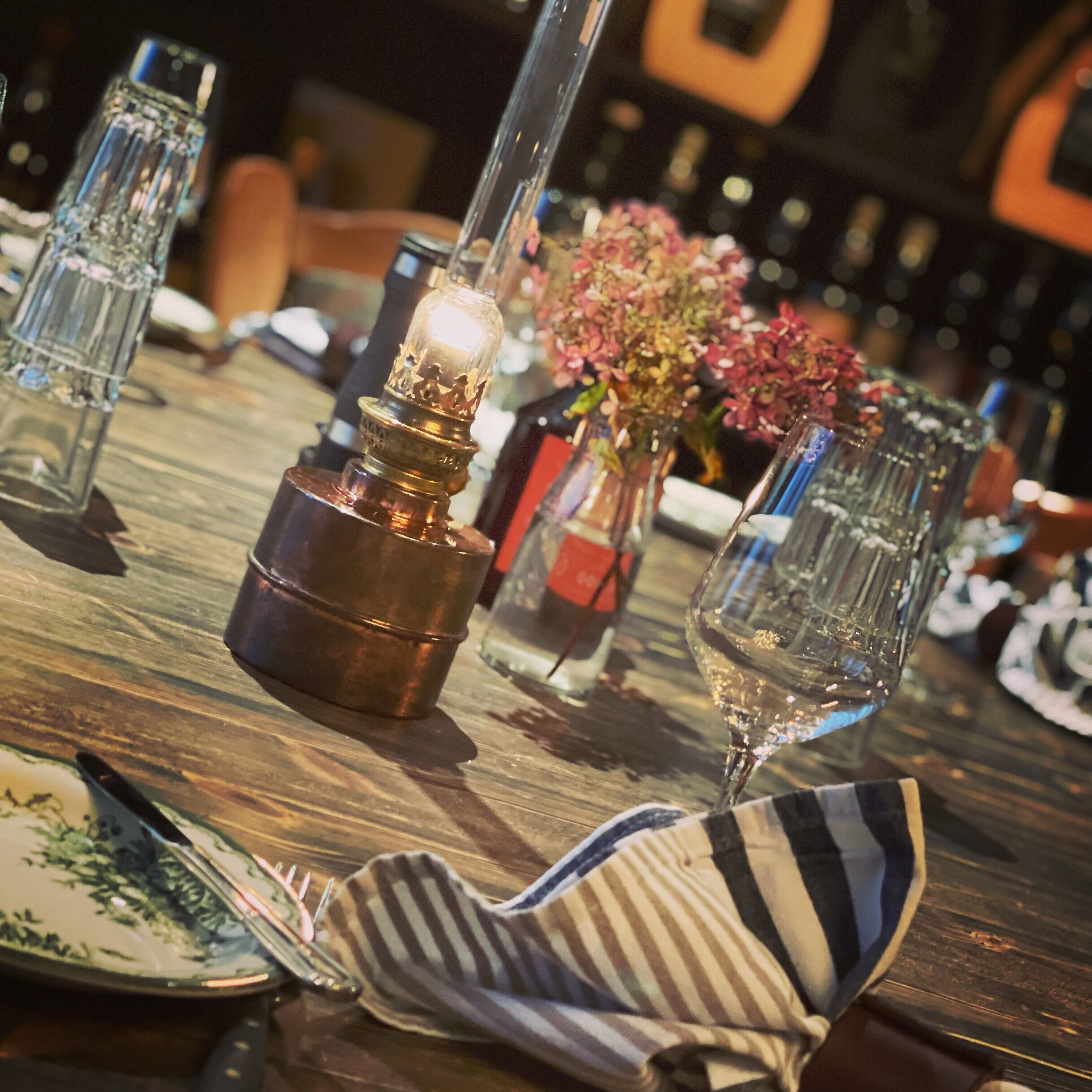 Una mesa de comedor con vela, cristalería y servilleta a rayas.
