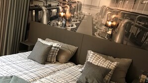 Ein Schlafzimmer mit einem großen Bett, einem Spiegel an der Kopfteil und einem Nachttisch mit einer Lampe.