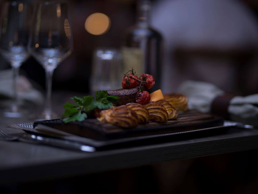 A dining table with a plate of food, a bottle, and glasses.