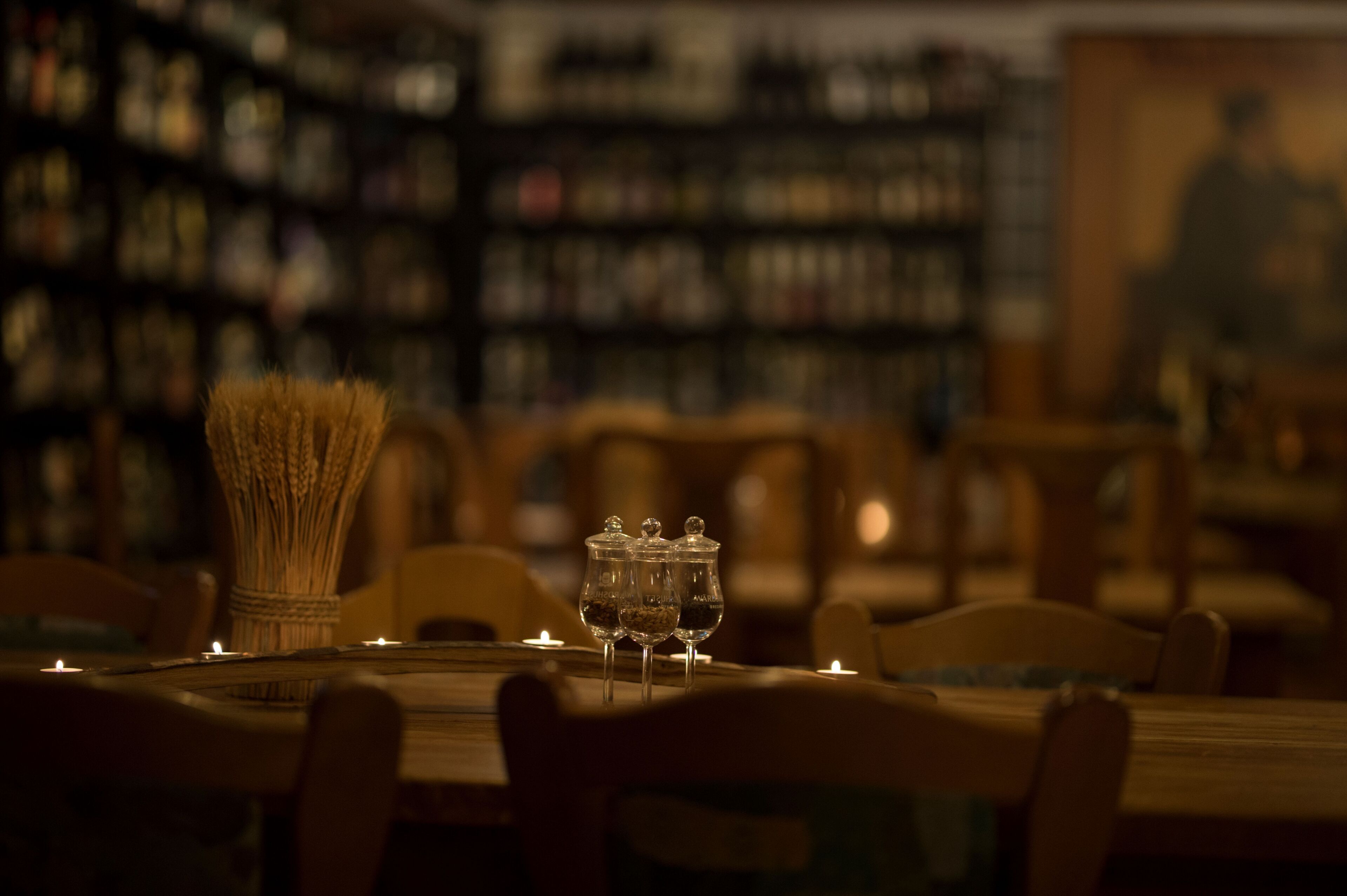 A dimly lit library with bookshelves and a table with glasses and a vase.