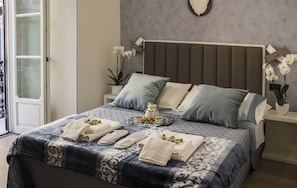 A neatly made bed with towels, a tray of breakfast items, and a potted orchid on the nightstand. - Superior Sky Apartment - Napoli Mariana Luxury (Napoli)