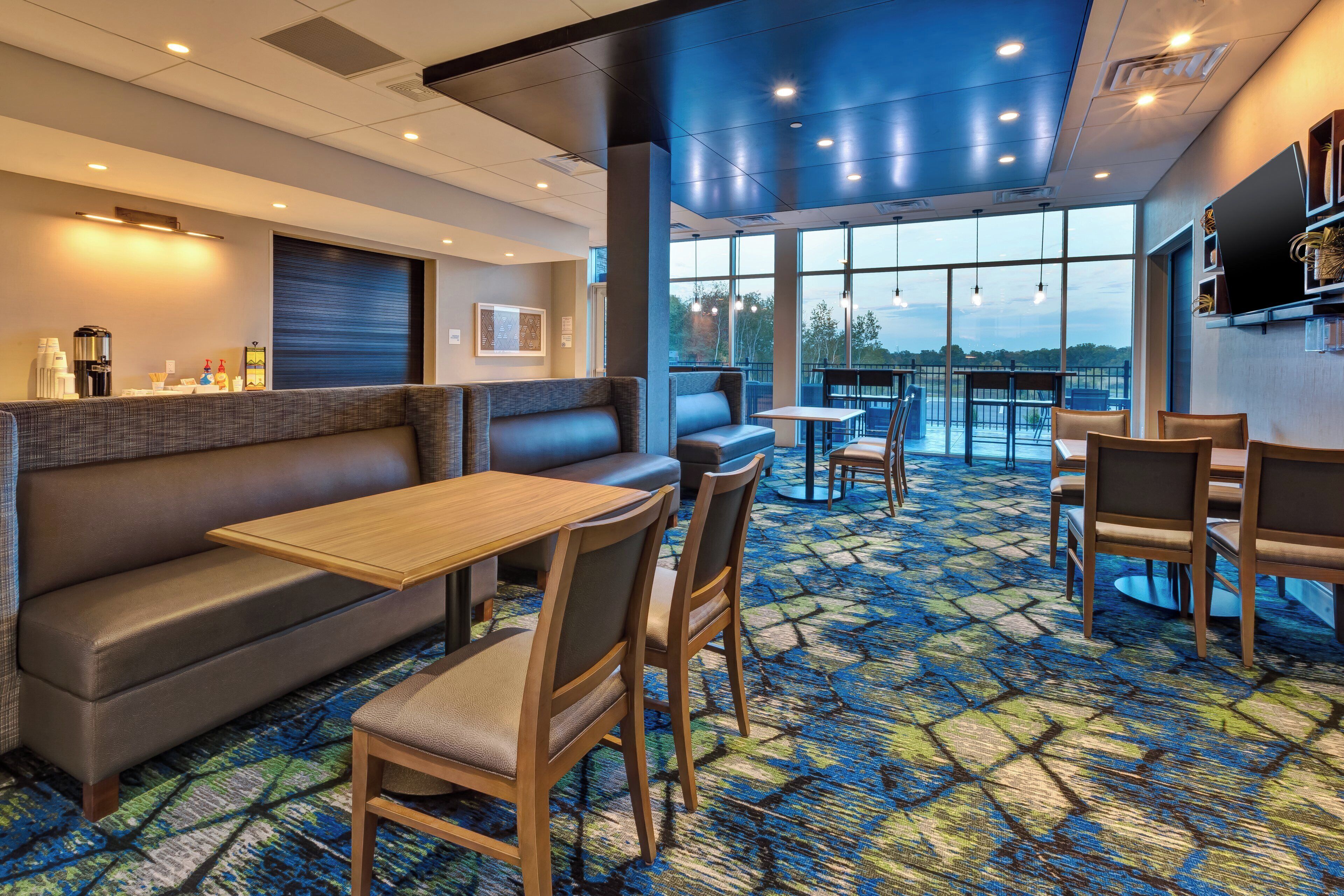 Comedor de hotel con asientos tipo cabina, un bar y vistas al exterior.
