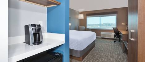 A hotel room with a bed, a desk, a coffee maker, a microwave, and a window with a view.
