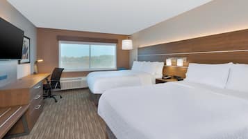 A hotel room with two beds, a desk, a chair, a TV, and a large window.