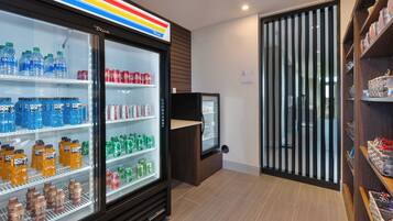 Un refrigerador para bebidas repleto de diversas opciones, una pequeña vitrina expositora y piso de madera.