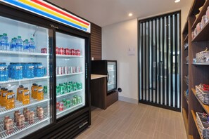 A beverage refrigerator stocked with various drinks, a small display case, and a wooden floor. - Holiday Inn Express & Suites Cedar Springs – Grand Rapids N by IHG (Cedar Springs)