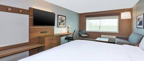 A hotel room with a large bed, a desk with a chair, a flat-screen TV, and a window with a view.