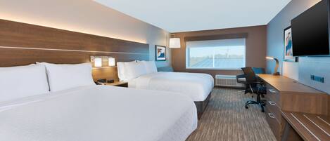 A hotel room with two beds, a desk, a chair, and a TV.