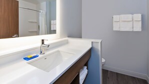 Een moderne badkamer met een witte wastafel, een spiegel en een handdoekhouder.