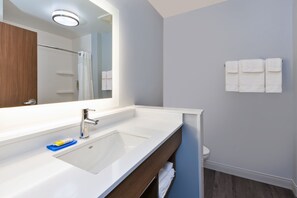 Uma casa de banho moderna com uma pia branca, um espelho e um porta-toalhas.