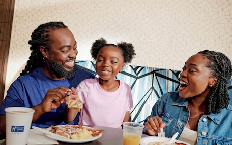 A family dining at a table with a patterned wall in the background.