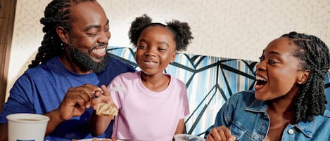 A family dining at a table with a patterned wall in the background.