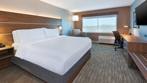 Een hotelkamer met een groot bed, een bureau, een stoel, een televisie en een raam met uitzicht.