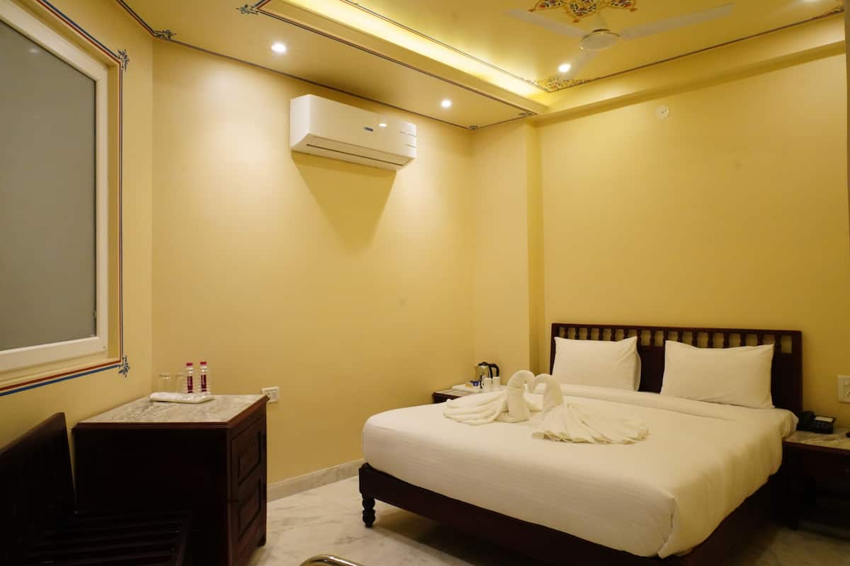 Una habitación de hotel con una cama, mesita de noche y un equipo de aire acondicionado.