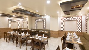 Un restaurante con varias mesas y sillas de madera, dispuesto en un espacio amplio.