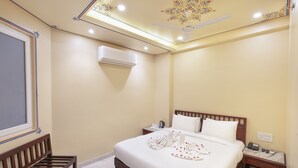 Una habitación de hotel con una cama, un banco de madera, una mesita de noche y un ventilador de techo.