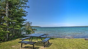 Una mesa de picnic y bancos junto a un lago con cielo despejado.