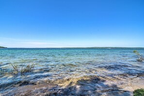 Ein ungehinderter Blick auf einen Strand mit ruhigem Wasser und weiter Küste.