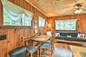 Relax in this inviting room with a dining table, sofa, and ceiling fan.