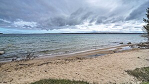 En strand med sandet bredde, roligt vand og en overskyet himmel.