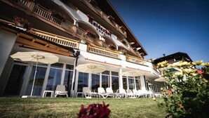 Un hôtel doté d’une terrasse, de grandes fenêtres et de balcons agrémentés de jardinières.