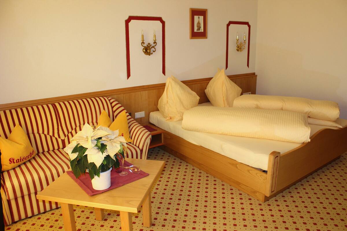 Una habitación con una cama, un sofá y una mesa con una planta en maceta.