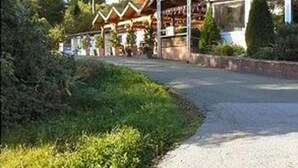 Eine Lodge mit überdachter Terrasse, umgeben von Bäumen und einem Kiesweg.