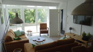 Ein Wohnzimmer mit einer Couch, Sesseln, einem Couchtisch und einem Fernseher.