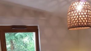 Ein Schlafzimmer mit zwei Betten, einem Fenster, einer Pendelleuchte und einem Nachttisch mit einer Lampe.