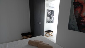 A bedroom with a bed, towels, a small wooden stool, and a wall-mounted picture. - White House Puerto Banus (Nueva Andalucía)