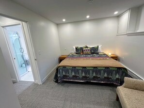 Ein Schlafzimmer mit einem Bett, einem Nachttisch, einer Lampe und einer Tür zu einem Badezimmer.