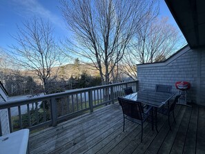 Eine Holzterrasse mit Tisch und Stühlen, mit Blick auf eine Berglandschaft.