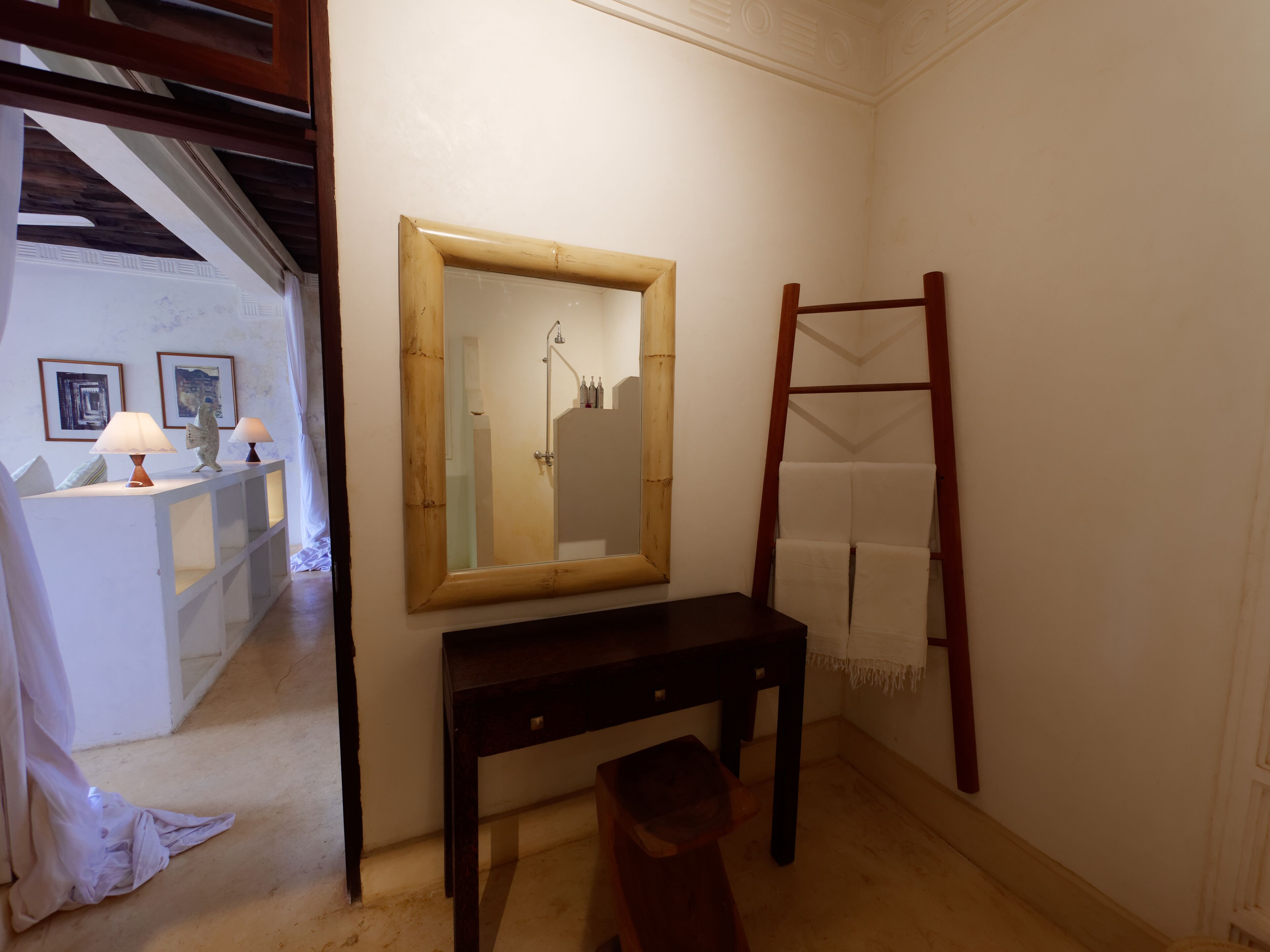 Un bagno con una panca in legno, uno specchio e un portasciugamani.