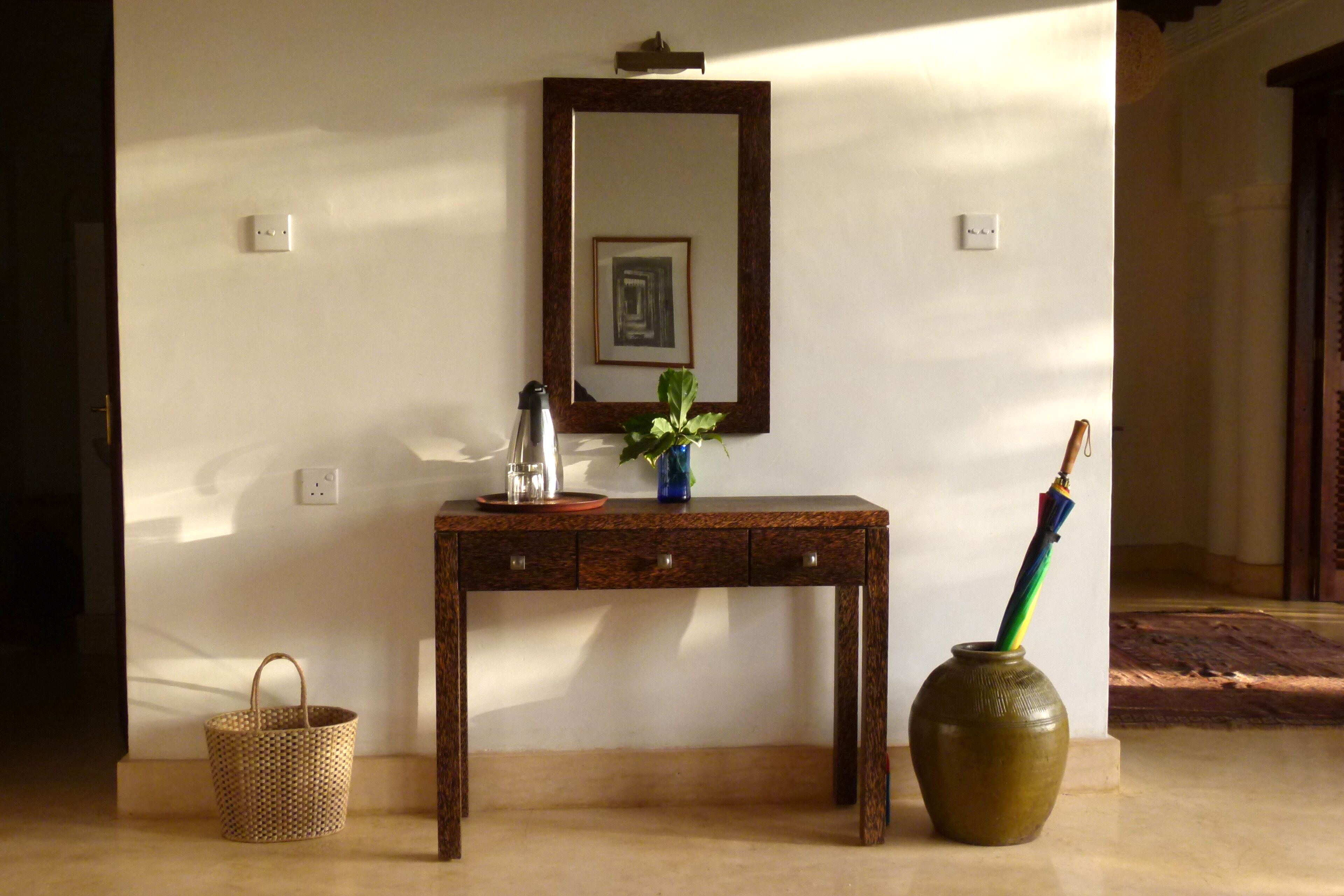 Una consola de madera con un florero y un cuadro enmarco.