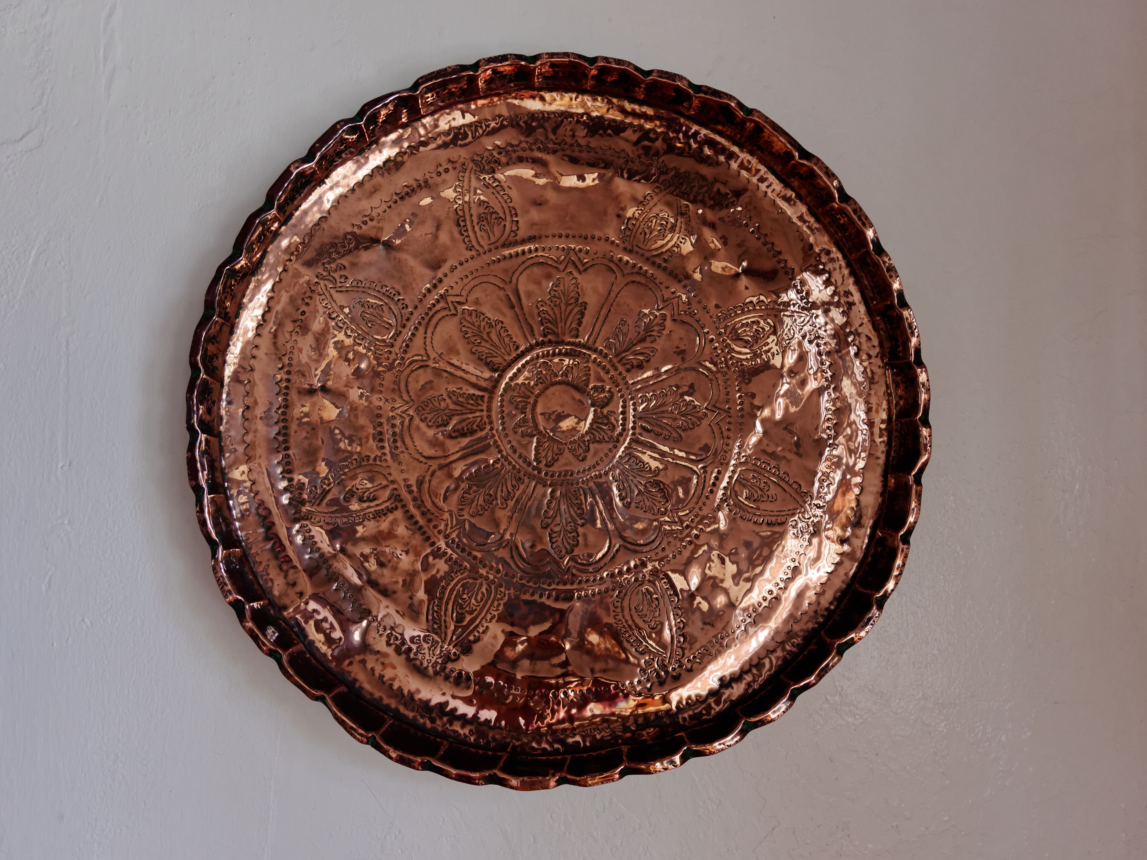 A decorative copper plate with intricate floral and paisley patterns.