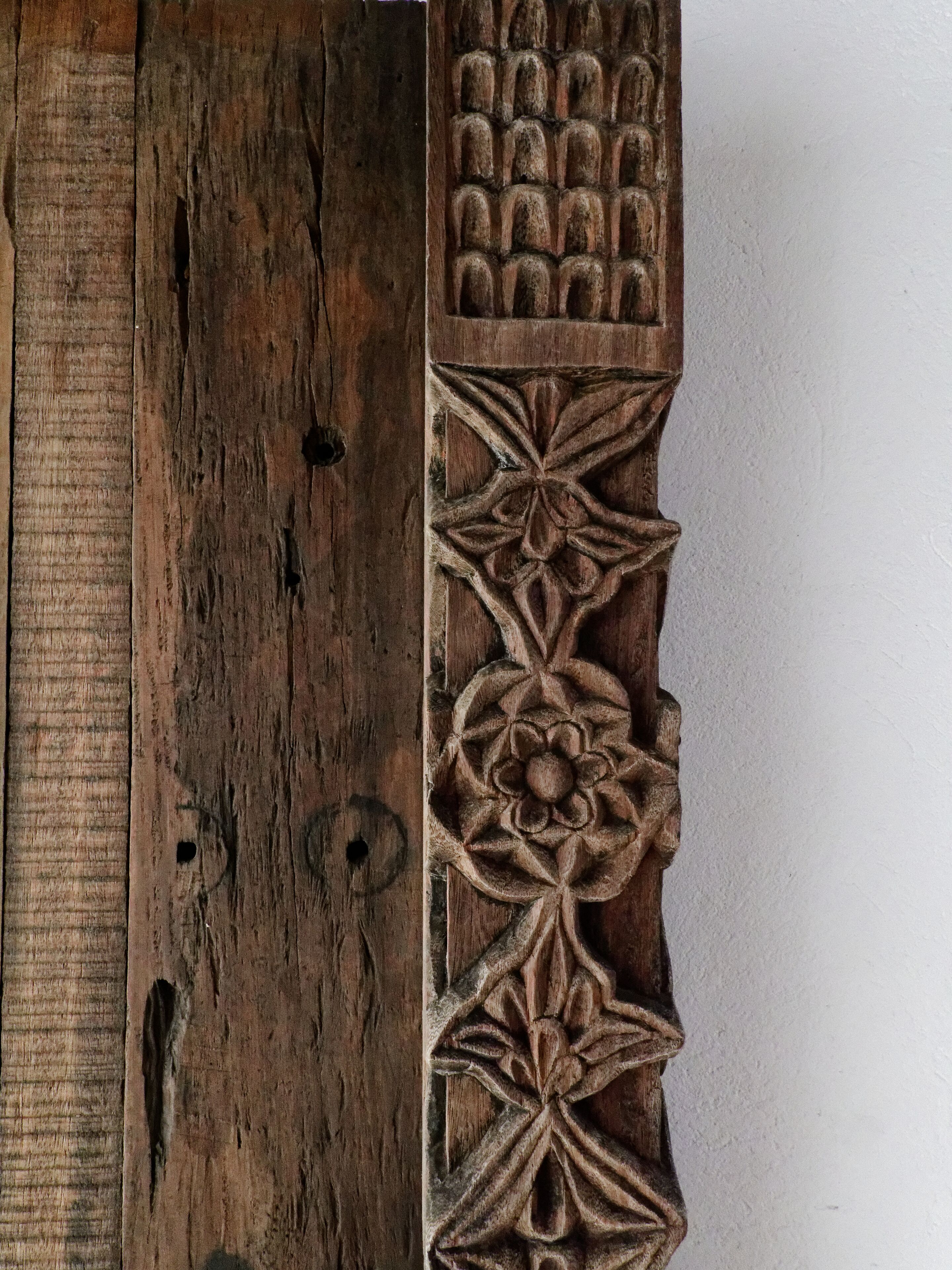 A wooden panel with intricate carvings, including a geometric pattern and a floral design.