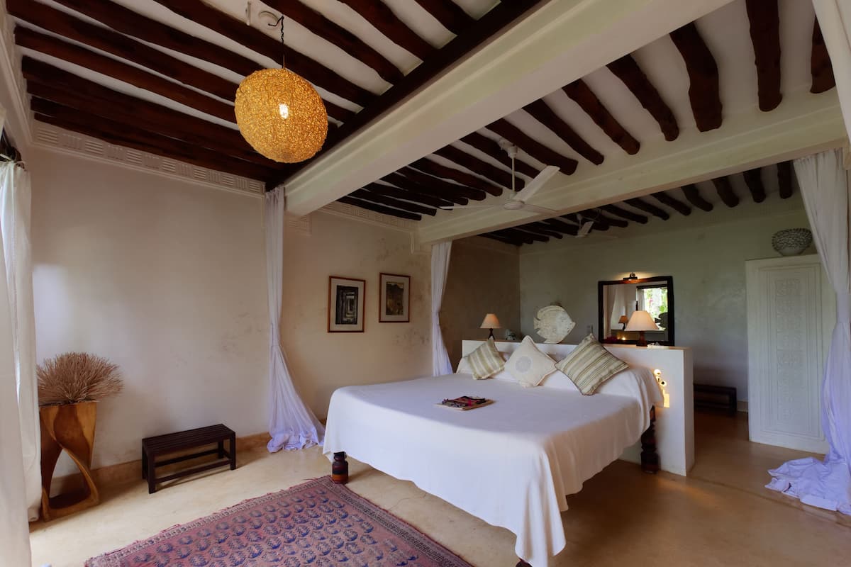 A bedroom with a large bed, a hanging light fixture, and a ceiling fan.
