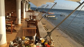 A beachside restaurant with outdoor seating, tables, and chairs, overlooking the sea. - Peponi Hotel (Lamu)