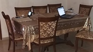 Ein Essbereich mit einem runden Tisch, sechs Stühlen und einem Laptop.