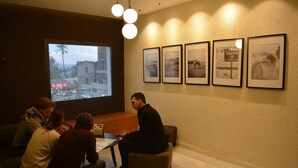 Ein Konferenzraum mit einem großen Fenster, einem Tisch und vier gerahmten Bildern an der Wand.