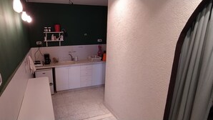 Eine kleine Küche mit weißer Arbeitsplatte, Spüle und kleinem Kühlschrank.